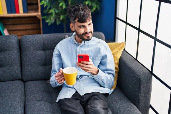 Young Hispanic Man Drinking Coffee Using Smartphone Home — Stock fotografie