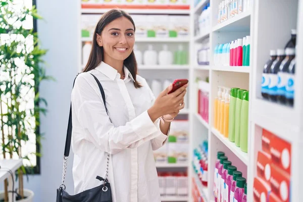 Young Beautiful Hispanic Woman Customer Smiling Confident Using Smartphone Pharmacy — 스톡 사진