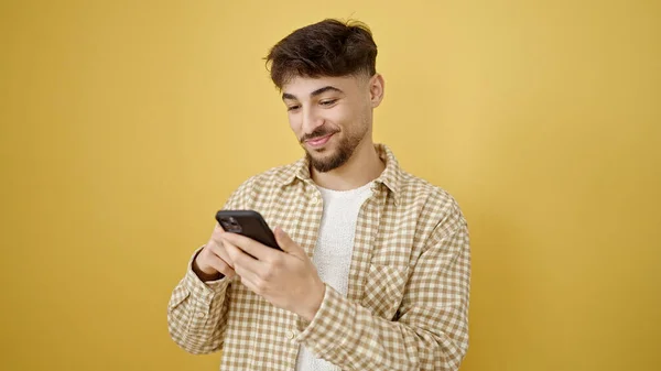 Молодий Арабський Чоловік Посміхається Впевнено Використовуючи Смартфон Над Ізольованим Жовтим — стокове фото