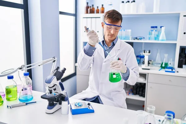 実験室で試験管に液体を注ぐ若い男科学者 — ストック写真