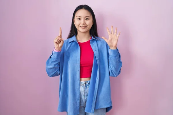 Mladá Asijská Žena Stojící Nad Růžovým Pozadím Ukazující Ukazující Nahoru — Stock fotografie