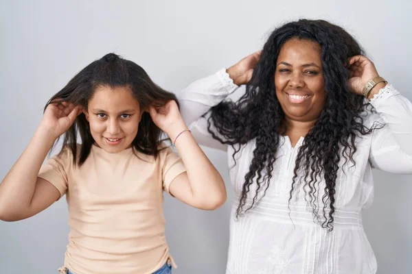 母親と若い娘の白い背景に指で耳を引く笑みを浮かべて立って 面白いジェスチャー オーディション問題 — ストック写真