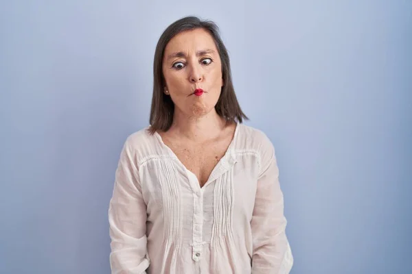 唇で魚の顔を作る青の背景に立っている中年のパニック女性 狂気とコミカルなジェスチャー 面白い表現 — ストック写真
