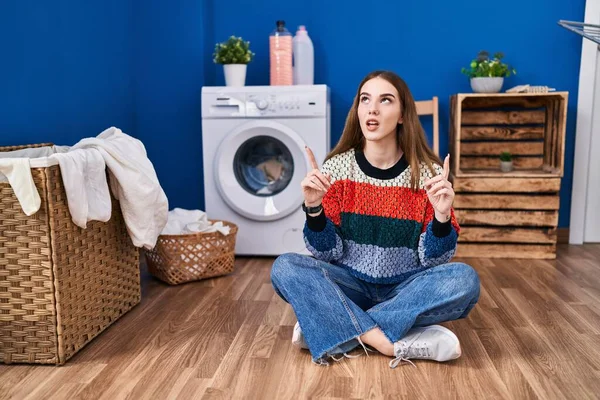 Young Hispanic Girl Doing Laundry Amazed Surprised Looking Pointing Fingers — Stock Photo, Image