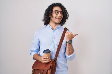 Kıvırcık saçlı İspanyol bir adam bir fincan kahve içerken gülümseyen ve başparmağıyla yüzünü gösteren bir gülümseme.. 