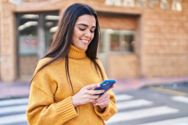 Sokakta akıllı telefon kullanan, kendine güvenen genç İspanyol kadın.