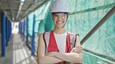 Güzel İspanyol kadın mimar gülümsüyor. Kollarını kavuşturup caddede duruyor.