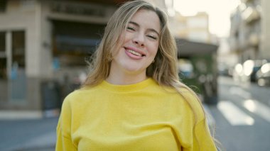 Sokakta kendine güvenen genç sarışın kadın gülümsüyor