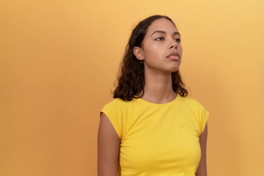 Young african american woman standing with serious expression over isolated yellow background