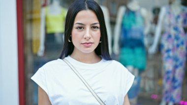 Genç ve güzel İspanyol kadın giyim mağazasında ciddi bir ifadeyle dikiliyor.