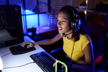 Young african american woman streamer playing video game using computer at gaming room