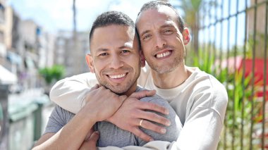 Two men couple smiling confident hugging each other at street