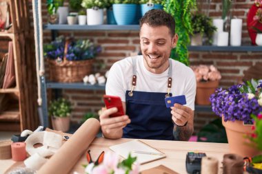 Çiçekçide akıllı telefon kullanan İspanyol bir çiçekçi.