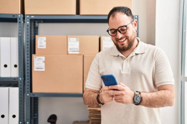 Ofiste akıllı telefon kullanan Latin asıllı genç bir e-ticaret işçisi.