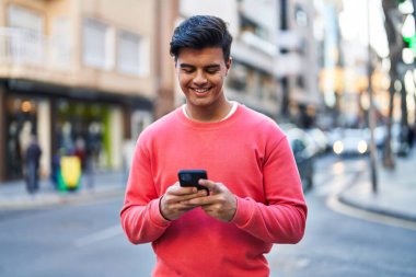 Sokakta akıllı telefon kullanan, kendine güvenen genç bir İspanyol.