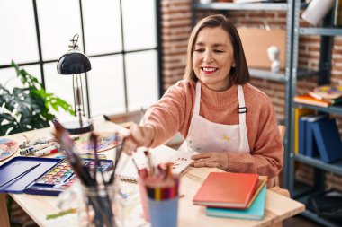 Middle age woman artist drawing on notebook at art studio