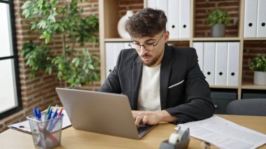 Genç Arap iş adamı ofiste çalışırken dizüstü bilgisayar kullanıyor.