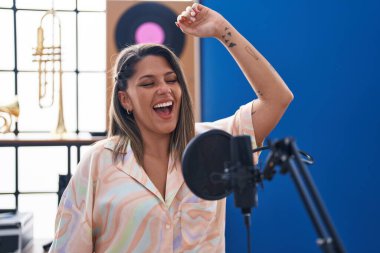 Young hispanic woman artist singing song at music studio