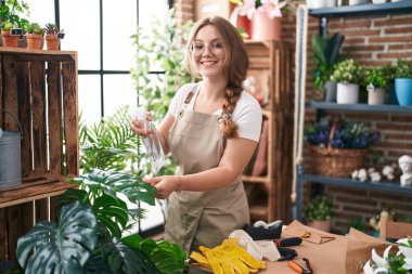 Çiçekçide su karıştırıcı kullanan genç sarışın kadın.