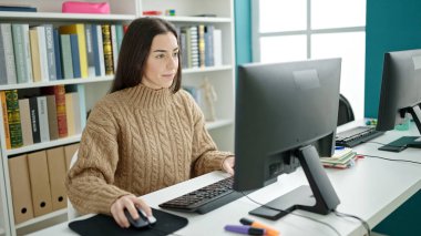 Genç, güzel İspanyol bir kız öğrenci üniversite sınıfında bilgisayar kullanıyor.