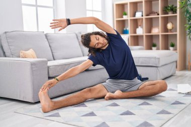 Young hispanic man training yoga at home