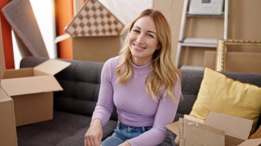 Genç, güzel, İspanyol bir kadın yeni evinde kendine gülerek duruyor.