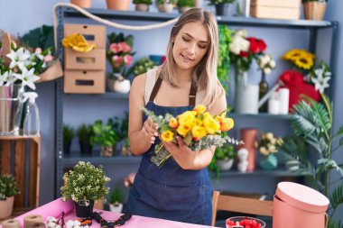 Young caucasian woman florist holding bouquet of flowers at florist