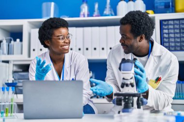Laboratuvarda bilgisayar ve mikroskop kullanan Afrikalı erkek ve kadın bilim adamları
