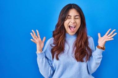 Mavi arka planda duran Latin kökenli genç bir kadın başarının çılgınlığını kollarını kaldırıp, gözlerini kapatarak ve heyecanla bağırarak kutluyor. Kazanan konsept 