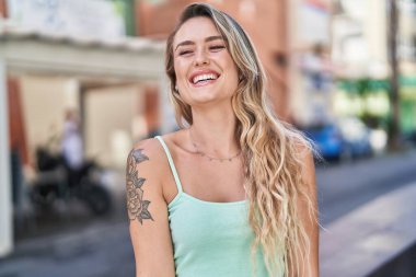Young blonde woman smiling confident looking to the side at street
