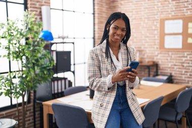 Ofiste akıllı telefon kullanan Afrikalı Amerikalı iş kadını.