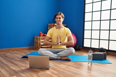 Young caucasian man smiling confident having online yoga class at sport center