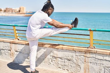 Afrika kökenli Amerikalı kadın deniz kenarında üstsüz esneme bacakları.