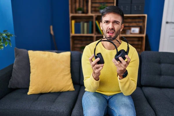 Kırık kulaklıkları olan İspanyol bir adam budala ve kafası karışmış bir ifade takınıyor. şüphe kavramı. 