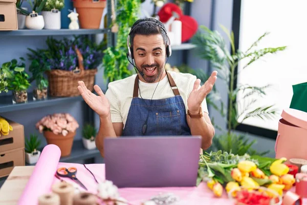 stock image Hispanic man with beard working at florist shop using laptop celebrating achievement with happy smile and winner expression with raised hand 