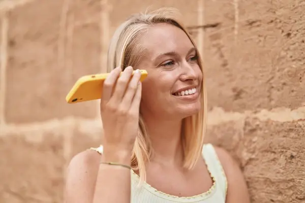 Молода Блондинка Посміхається Впевнено Слухаючи Аудіоповідомлення Смартфону Над Ізольованим Цегляним — стокове фото