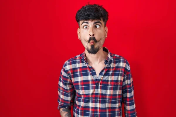 Jonge Spaanse Man Met Baard Die Rode Achtergrond Staat Vissengezicht — Stockfoto