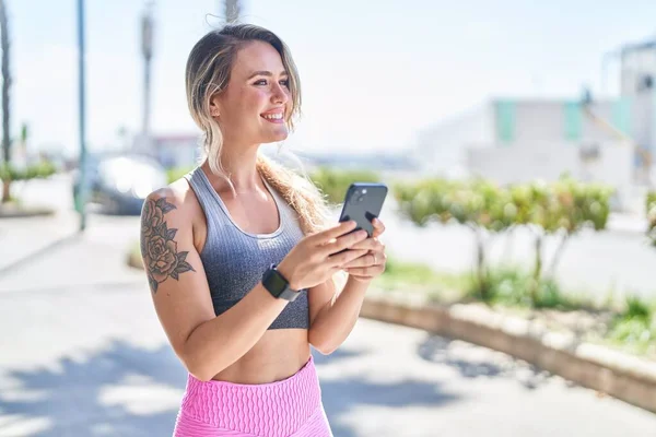 stock image Young blonde woman wearing sportswear using smartphone at street