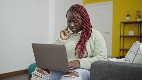 Afrikanerin Mit Geflochtenen Haaren Benutzt Laptop Mit Besorgtem Gesichtsausdruck Hause — Stockfoto