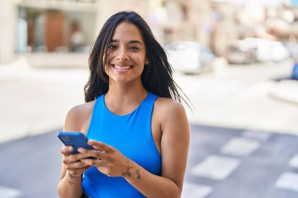 年轻的惊慌失措的女人在街上用智能手机充满自信地微笑 — 图库照片