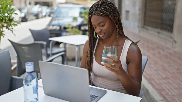 Mujer Afroamericana Sosteniendo Vaso Agua Usando Portátil Terraza Cafetería — Foto de Stock