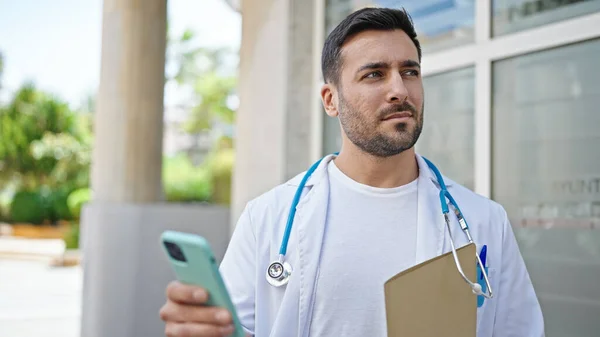 Junger Hispanischer Arzt Hält Krankenakte Mit Smartphone Krankenhaus — Stockfoto