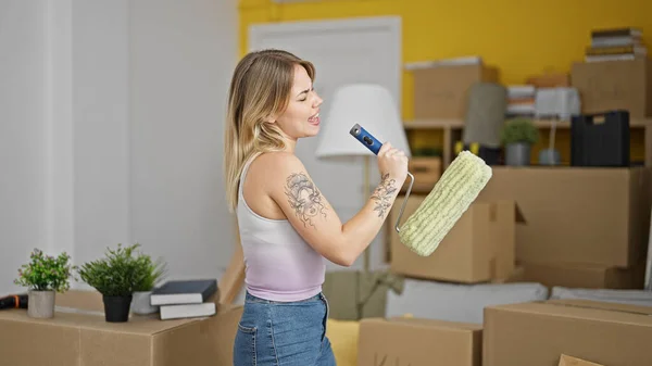 Mujer Rubia Joven Cantando Canción Usando Rodillo Pintura Como Micrófono —  Fotos de Stock