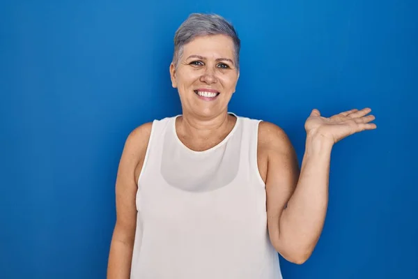 Orta Yaşlı Beyaz Bir Kadın Mavi Arka Planda Dikiliyor Gülümsüyor — Stok fotoğraf