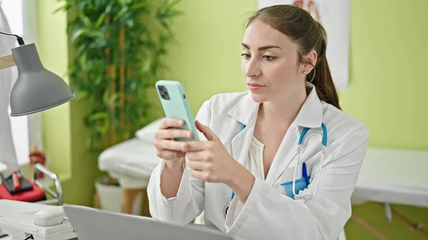 Young Beautiful Hispanic Woman Doctor Using Smartphone Working Clinic — Stock fotografie