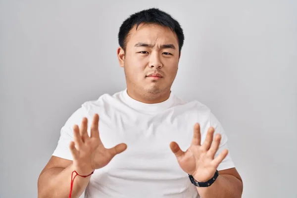 白い背景の上に立っている若い中国人男性は 恐怖と嫌悪感の表現で拒絶と拒否を示す手のひらを移動します 立ち止まって禁止 — ストック写真