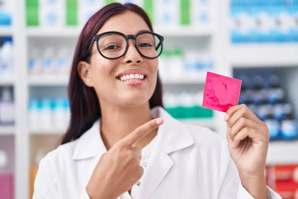 Young Hispanic Woman Working Pharmacy Holding Condom Smiling Happy Pointing — Stock Photo, Image