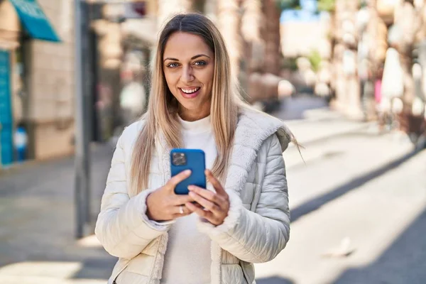 Sokakta akıllı telefon kullanan kendine güvenen genç bir kadın.