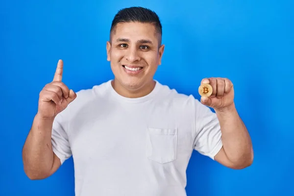 Hispánský Mladý Muž Držící Virtuální Měnu Bitcoin Překvapen Nápadem Nebo — Stock fotografie