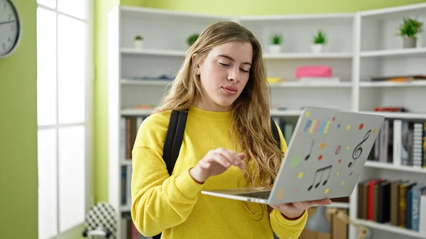 在图书馆大学 年轻的金发女学生背着背包 用笔记本电脑 — 图库照片